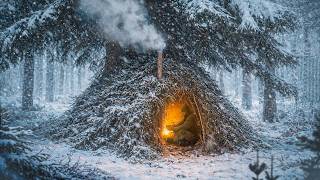 Bushcraft in a snowstorm. Building a warm and cozy shelter from branches under a spruce tree thumbnail